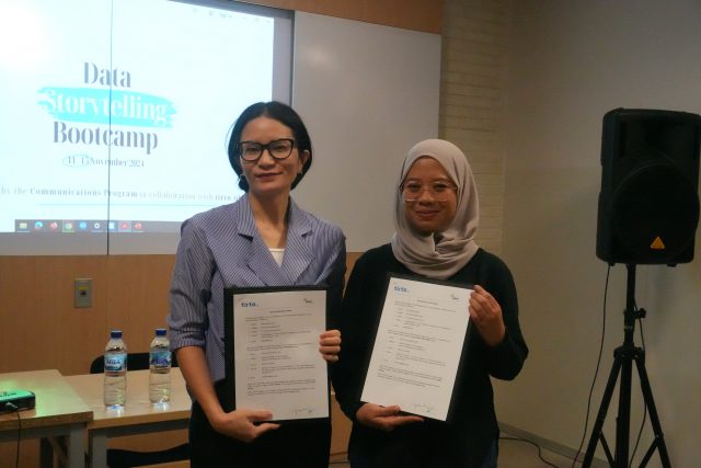 Ketua Jurusan Communication Program, BINUS University International berfoto dengan Program Development manager dari tirto.id sambil memegang surat perjanjian kerjasama yang telah ditandatangani