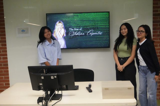 Students pose in front of a screen showing their Data Storytelling project title